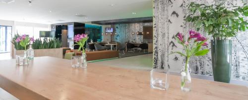 a table with vases of flowers on top of it at Novotel Rotterdam - Schiedam in Schiedam