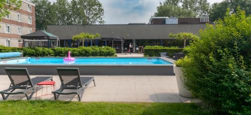 a swimming pool with two chairs and a pink float at Novotel Rotterdam - Schiedam in Schiedam