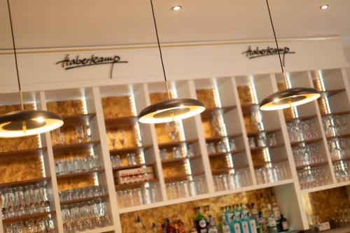 a bar with several chandeliers and shelves of wine glasses at Hotel Haberkamp in Achim