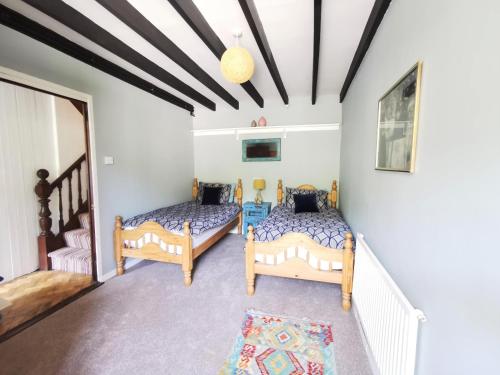two beds in a room with white walls at Wellstone Cottages - Jasmine in Llanfyrnach