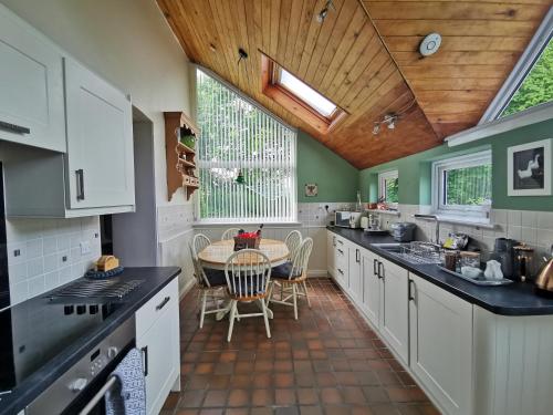 uma cozinha com armários brancos e uma mesa em Wellstone Cottages - Jasmine em Llanfyrnach