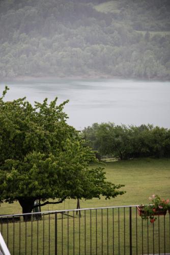 a fence with a tree in front of a lake at La Poiana in Barrea