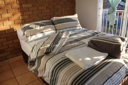 a couple of beds sitting next to a brick wall at Warm, Comfy Duplex 5min Walk To North Park Mall in Pretoria