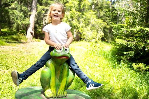 a little girl sitting on top of a frog statue at Kinderhotel Lärchenhof in Obsteig