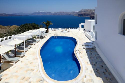 a swimming pool with chairs and a view of the ocean at Santorini View in Akrotiri