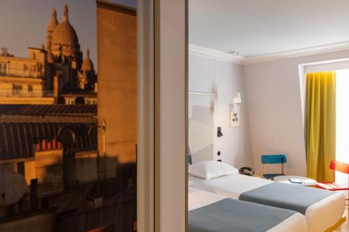 パリにあるホテル ドゥ ラ ペのベッド2台と窓が備わるホテルルームです。