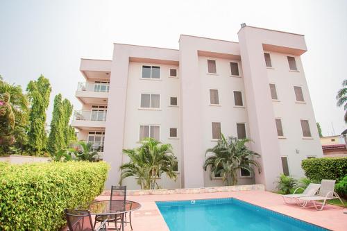 a large white building with a swimming pool and chairs at Bertha's Court D-Plus Apartments in Greenhill