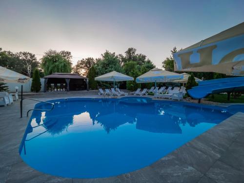 ein großer blauer Pool mit Stühlen und Sonnenschirmen in der Unterkunft Club Hotel Pegasus in Tiszaug