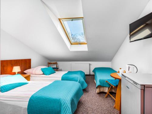 a attic room with two beds and a window at Orion Dom Gościnny in Dziwnów