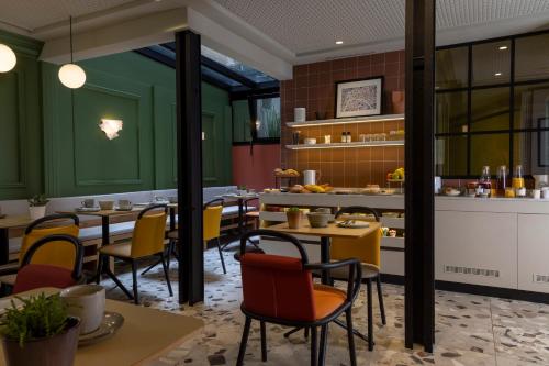 a restaurant with green walls and tables and chairs at Hôtel De La Paix in Paris
