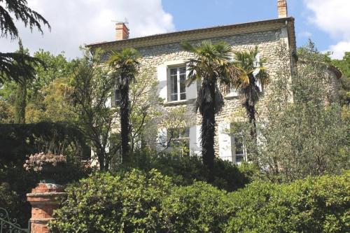an old stone house with palm trees in front of it at Domaine La Tour - SPA - Jacuzzi - Sauna - Massage - 4 SAISONS - Piscine Chauffée Toute l'année - Heated POOL - 800m City Centre Nyons in Nyons
