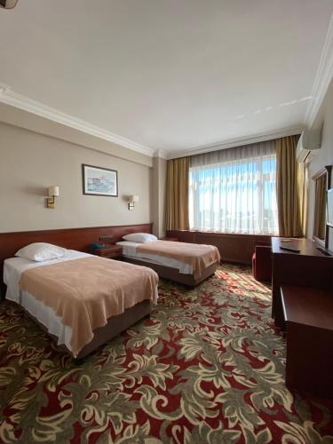 イスタンブールにあるホテル モノポールのベッド2台と大きな窓が備わるホテルルームです。