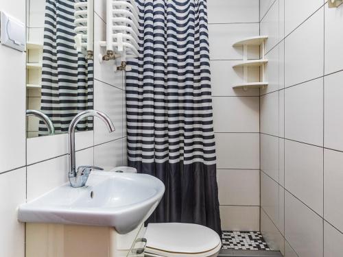 a bathroom with a sink and a toilet and a shower curtain at Orion Dom Gościnny in Dziwnów