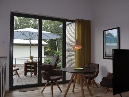 sala de estar con mesa, sillas y sombrilla en Ferienwohnungen Seerose, en Bad Zwischenahn