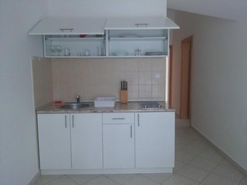 Una cocina con gabinetes blancos y un fregadero. en Luxury Villas Marko, en Tivat
