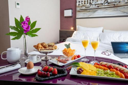 a breakfast tray with fruit and drinks on a bed at Hotel St Martin by OMNIA hotels in Rome