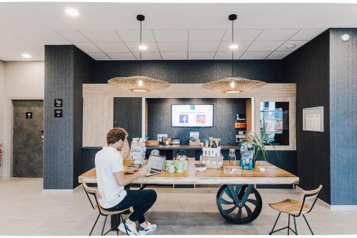 a man sitting at a counter in a coffee shop at ibis Styles Contres-Cheverny in Le Controis En Sologne
