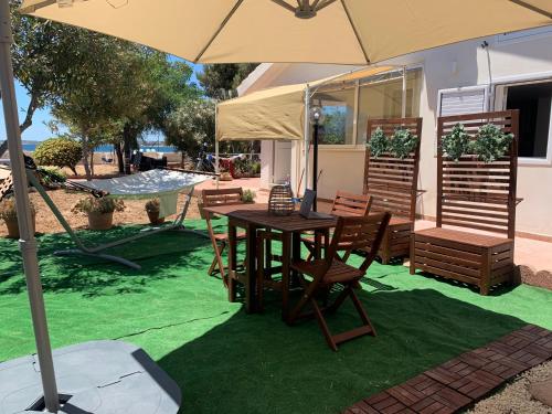 a table and chairs with an umbrella on green grass at La Caletta di Afrodite in Calabernardo