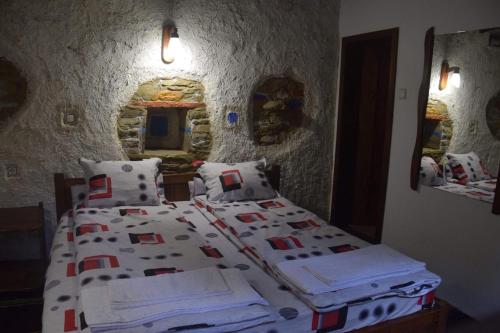 a bedroom with a bed with white sheets and pillows at Etnographic Houses in Dŭlbok Dol