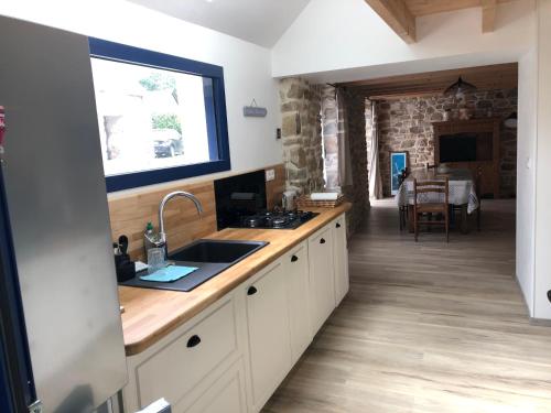 une cuisine avec un évier et un plan de travail dans l'établissement Charmante petite maison Rostiviec bord de mer, à Loperhet