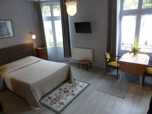 1 dormitorio con cama, mesa y escritorio en Hôtel des Thermes, en Bourbon-l'Archambault