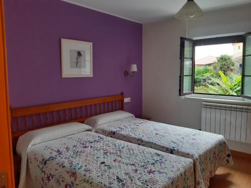 two beds in a bedroom with purple walls and a window at Hotel Las Terrazas in Tazones