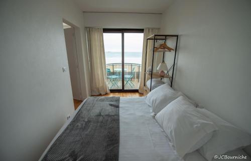 a bedroom with a bed with a view of the ocean at APPARTEMENT PLEINE VUE MER 34 Ch. du Sillon Saint-Malo Plage in Saint Malo