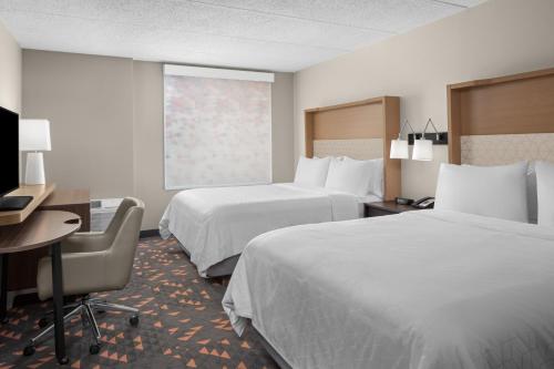 a hotel room with two beds and a desk at Holiday Inn Hasbrouck Heights-Meadowlands by IHG in Hasbrouck Heights