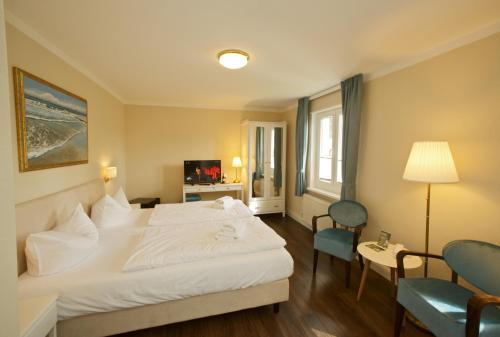 a hotel room with a white bed and two chairs at Panorama Hotel Lohme in Lohme