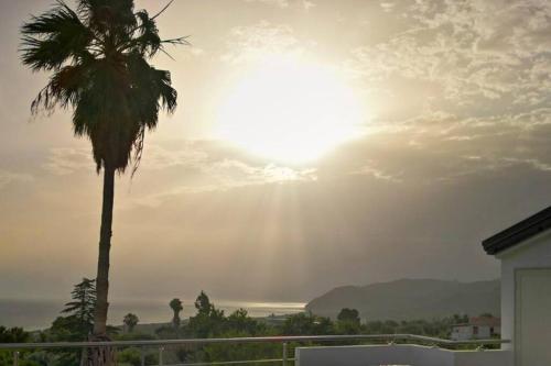 a palm tree and the sun in the sky at Loft incantevole con idromassaggio esterno privato in Patti
