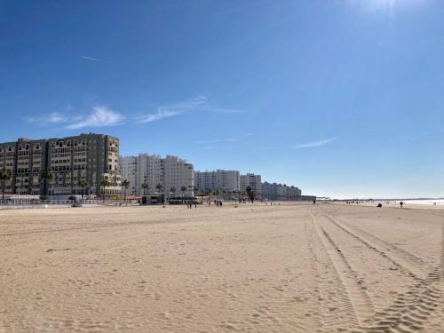 a sandy beach with buildings in the background at ESTUDIO BLEGAMAR TERRAZA - Playa, WiFi y Aparcamiento in El Puerto de Santa María