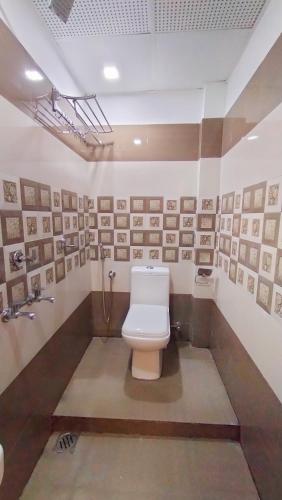 a bathroom with a toilet and pictures on the wall at Railview Residency in Alleppey