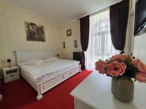 a bedroom with a white bed and a vase of flowers at Vila Sia in Bucharest