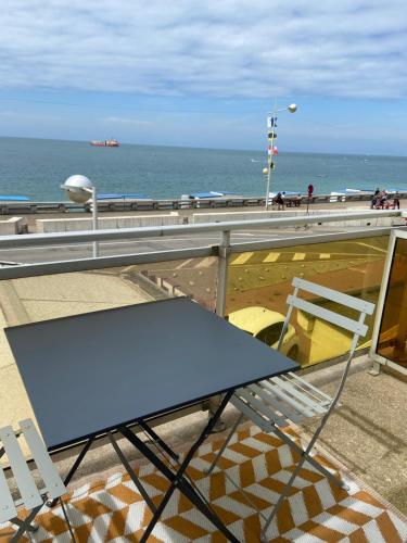 a blue table and chairs on a pier with the ocean at New Hôtel de la Mer in Fécamp
