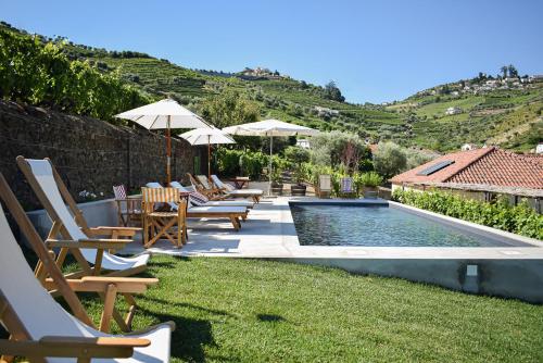 a pool with chairs and umbrellas in a yard at Quinta da Casa Amarela- Casas da Quinta - Turismo em Espaço Rural in Lamego