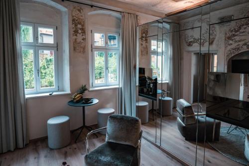 a living room with a chair and a table and windows at Gartenhäuschen by Hotel Goldene Rose in Dinkelsbühl