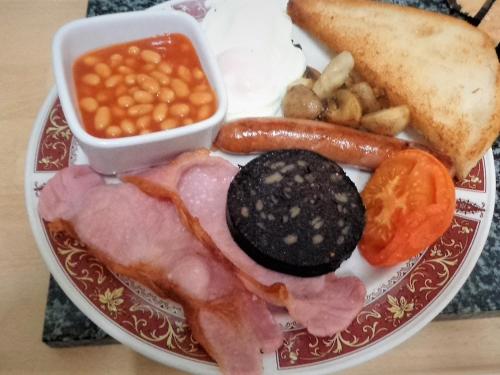 une assiette de nourriture avec de la viande, des haricots et du pain dans l'établissement The Almeria, à Blackpool