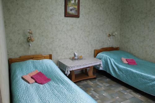 two beds in a room with blue sheets and a table at Guest House Na Lesnoy in Myshkin