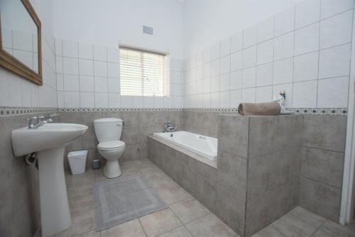a bathroom with a toilet and a tub and a sink at Hoogwater Family House in Wolseley
