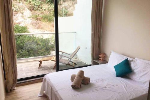 a bed with a teddy bear on it in front of a window at Mellieha Luxury Penthouse with sea & country views in Mellieħa