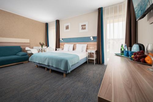Habitación de hotel con cama y sofá azul en Pensjonat Luan en Władysławowo