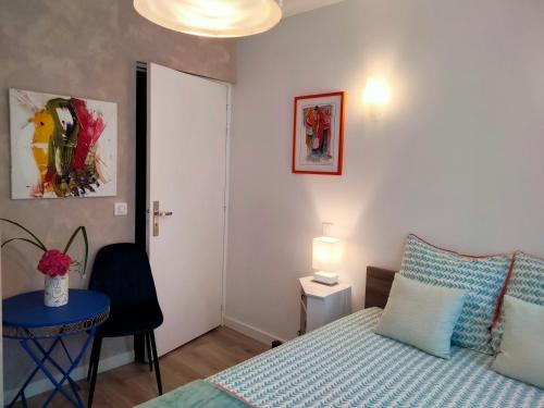 ein Schlafzimmer mit einem Bett, einem Tisch und einer Lampe in der Unterkunft Les Chambres Hautes d'Anastasia in Rodez