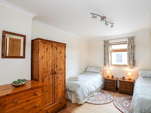 a bedroom with two twin beds and a wooden cabinet at Penrallt Fawr in Caernarfon