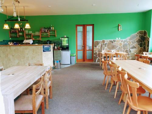 un restaurant avec des murs verts, des tables et des chaises en bois dans l'établissement Penzion Lumis, à Nová Role