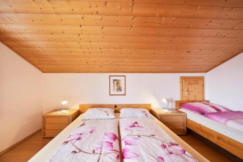 two beds in a room with wooden ceilings at Wieserhof Ferienwohnung Priml in Sarntal