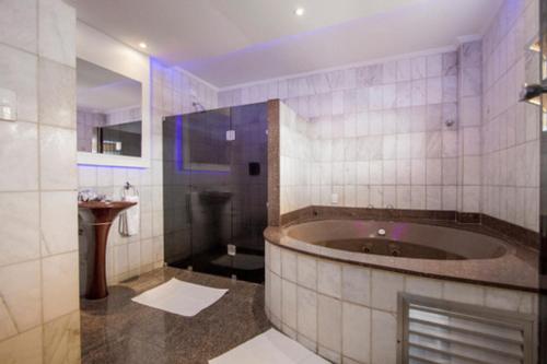 ein Badezimmer mit einer großen Badewanne und einem Waschbecken in der Unterkunft Carícia Hotel (Adult Only) in Santos