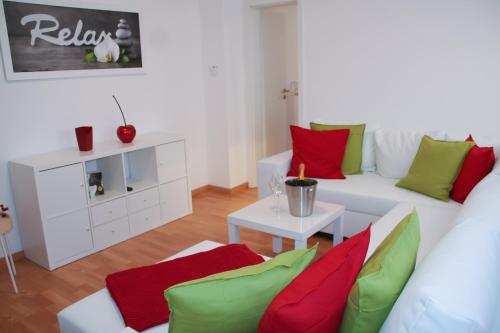 ein Wohnzimmer mit einer weißen Couch mit roten und grünen Kissen in der Unterkunft Premium Ferienwohnung Sonnenaufgang in Witzenhausen