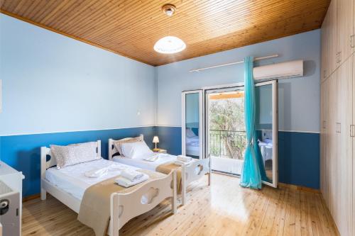 Olive Tree House في Evropoúloi: سريرين في غرفة بجدران زرقاء ونافذة