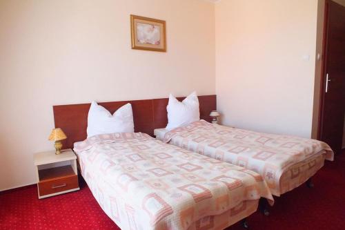 a hotel room with two beds and a night stand at Hotel Aleksander in Ustka