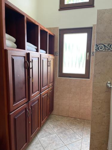 a bathroom with wooden cabinets and a window at Ocean Breeze Villa Carismar in Cabrera